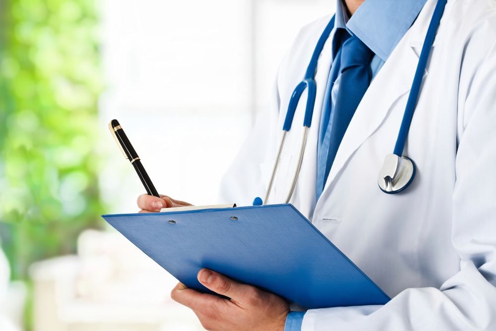 Doctor in a white coat writing on a blue clipboard | Doctor in Torba | Online Doctor & Online Prescription | E-rx.online