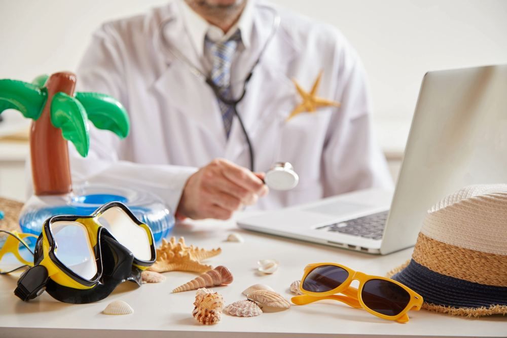 Doctor at a desk with beach holiday items, stethoscope and laptop | Find a Doctor Near You in Lara | Online Doctor & Online Prescription | E-rx.online